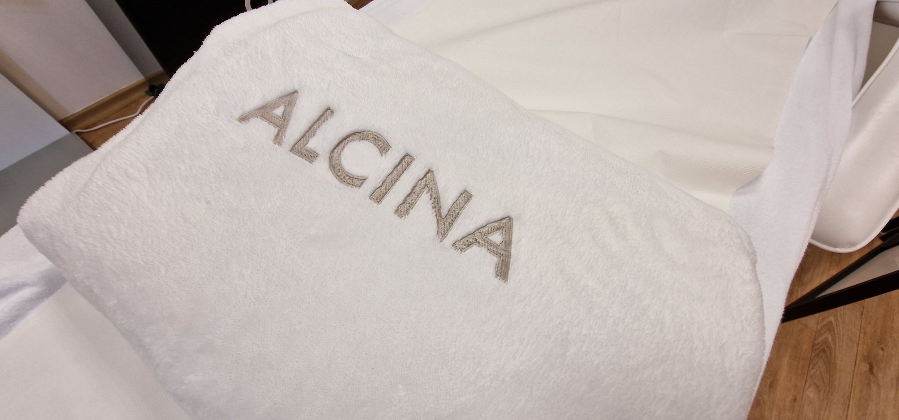 Bílý ručník s logem Alcina na ošetřovacím lehátku ve studiu Studio S